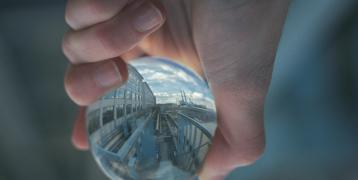 Hand holding a glass ball that reflects building