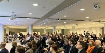 A group of people are sitting to listen to the presentation.