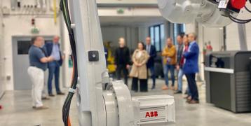 A group of people behind the arm of a robot