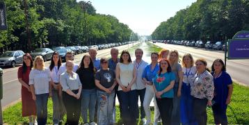 Group photos of participants from the SHARING project event, standing on a tree-lined avenue in Bucharest, Romania. Participants are smiling and engaged in informal conversation, showcasing the project's collaborative spirit and diverse representation.