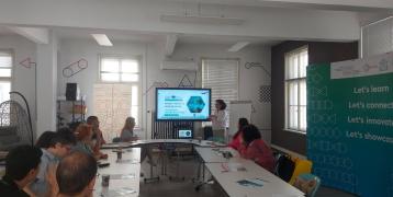 12 individuals sit around a table and look at powerpoint on SKYLA