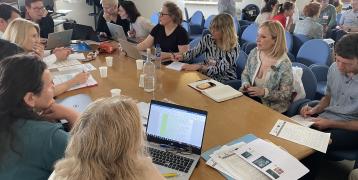 People sit in a room around a desk working