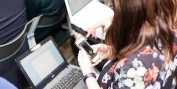 Woman checking her phone while using her laptop