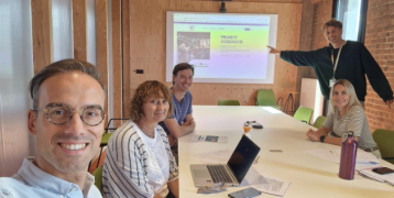 Stakeholders of creative sectors in Kortrijk in a meeting room, behind them there is a presentation.