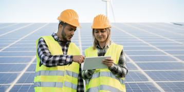 Male and female construction workers in front of solar panels