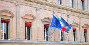 Building with 3 flags of the European Union, Italy and Bologna.