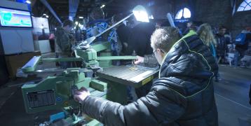 A variety of people using various machines to innovate and create.