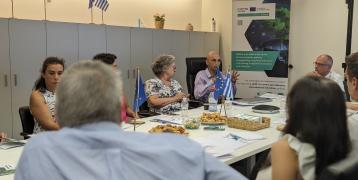 Stakeholders sit around a table, with the SKYLA poster in the background