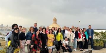A group of colleagues stand in front of a view in Malta