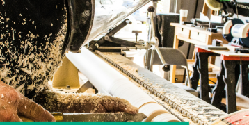Image showing a woodworker operating a machine in a woodworking shop, with sawdust flying from a lathe. The image also features the Interreg Europe logo and the text 'Newsletter #1' for the FBI4EU project, co-funded by the European Union.