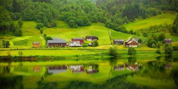Lush green mountain valley with a few houses on a lake shore