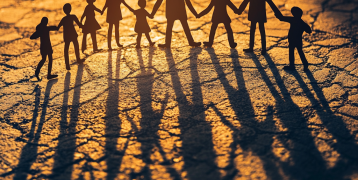 Silhouettes of paper-cut figures holding hands, casting long shadows on a textured surface in warm golden light, symbolizing unity and community. Silhouettes of paper-cut figures holding hands, casting long shadows on a textured surface in warm golden light, symbolizing unity and community.