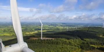 an arieal picture looking at wind turbines and a forest