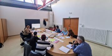 A group of people is sitting behind the table discussing integration in Litija, Slovenia. 