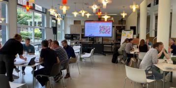 People are sitting around tables, engaging in a discussion during a session. 