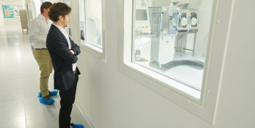 Two people looking at machines through a window Two people looking at machines through a window