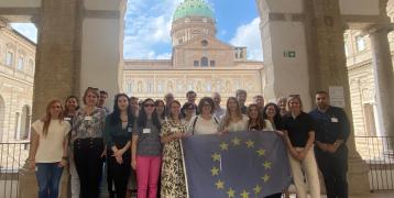 Group photo of PROXIMITIES partners standing holding EU flag with PROXIMITIES logo in corner