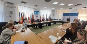 Participants at the MDLPA stakeholder meeting discussing inter-municipal cooperation and conclusions from the SHARING project's second interregional event. Flags of EU countries are displayed in the background.