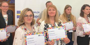 Women pose with certificates written in Ukrainian