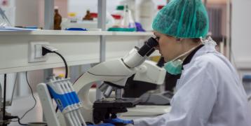 Researcher looking into a microscope