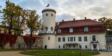 Castle in autumn park with colourful trees and leaves on the ground in October in Cesis, Latvia