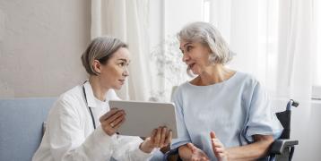 A doctor with a older patient using a connected tablet