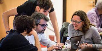 group of people working together and looking at a computer screen