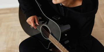 Person in black long sleeve playing accoustic guitar