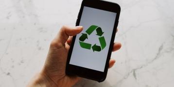 Hand holding phone with green recycling icon 
